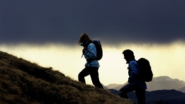 Zwei Wanderer vor Gewitterwolken beim Aufstieg | Bild: mauritius images / go-images
